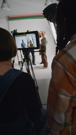 Vertical-Video-Of-Actors-With-Scripts-In-Rehearsal-Shooting-Movie-Or-Video-In-Studio-With-female-Director-And-Film-Crew-And-Watching-On-Monitor-2